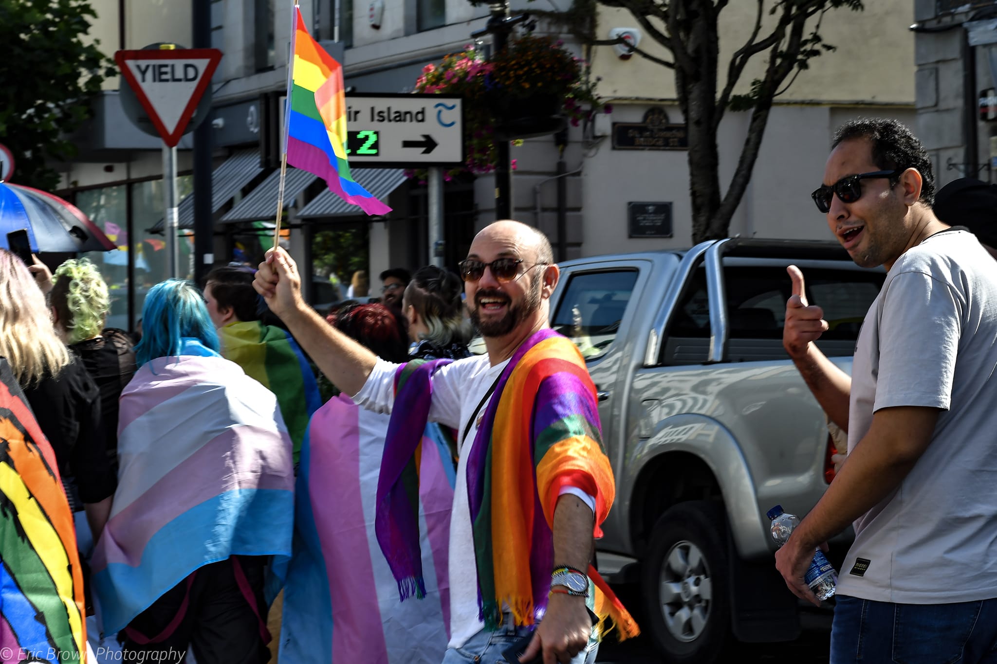 Man in parade waving pride flag